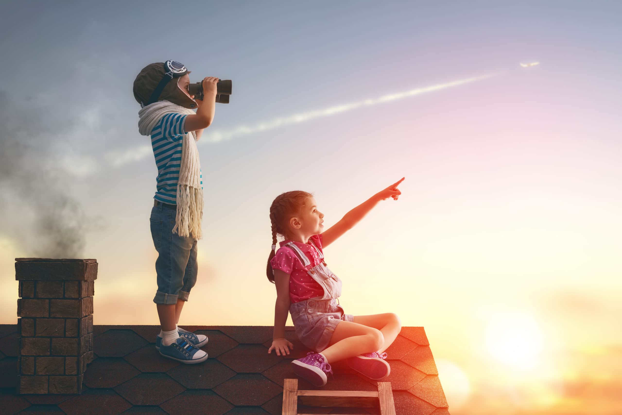 Two little children playing on the roof of the house and looking at the sky and dreaming of becoming a pilots.